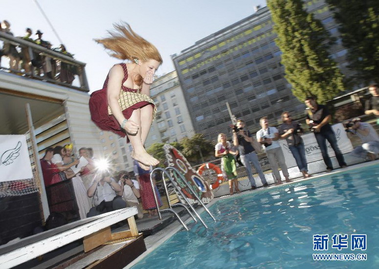 A girl wearing traditional costume jumps into a swimming pool during Alps village-girl style driving competition on June 16, 2012. (Xinhua/AFP)