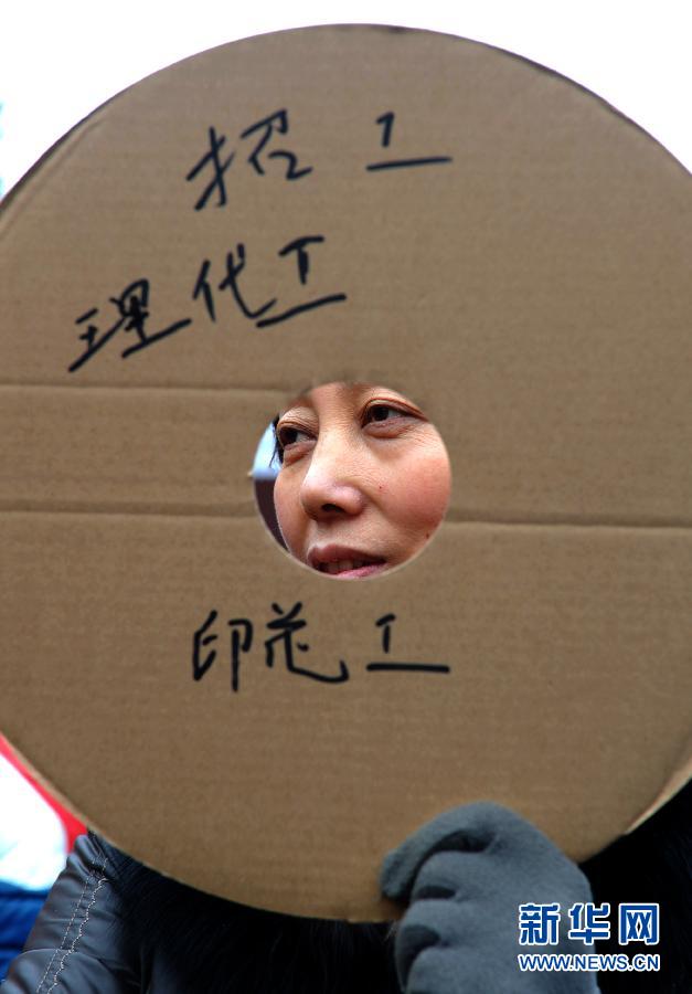 Recruiters from a small factory holding placards wait for job seekers outside the talent market of Yiwu in Zhejiang on Jan. 31, 2012.