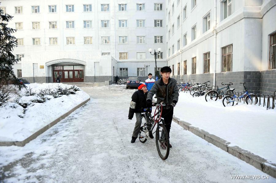 Wang Junsheng (R) drives his disabled classmate Jiang Jian on a bicycle to the canteen at school in Harbin, capital of northeast China's Heilongjiang Province, Dec. 19, 2012.  