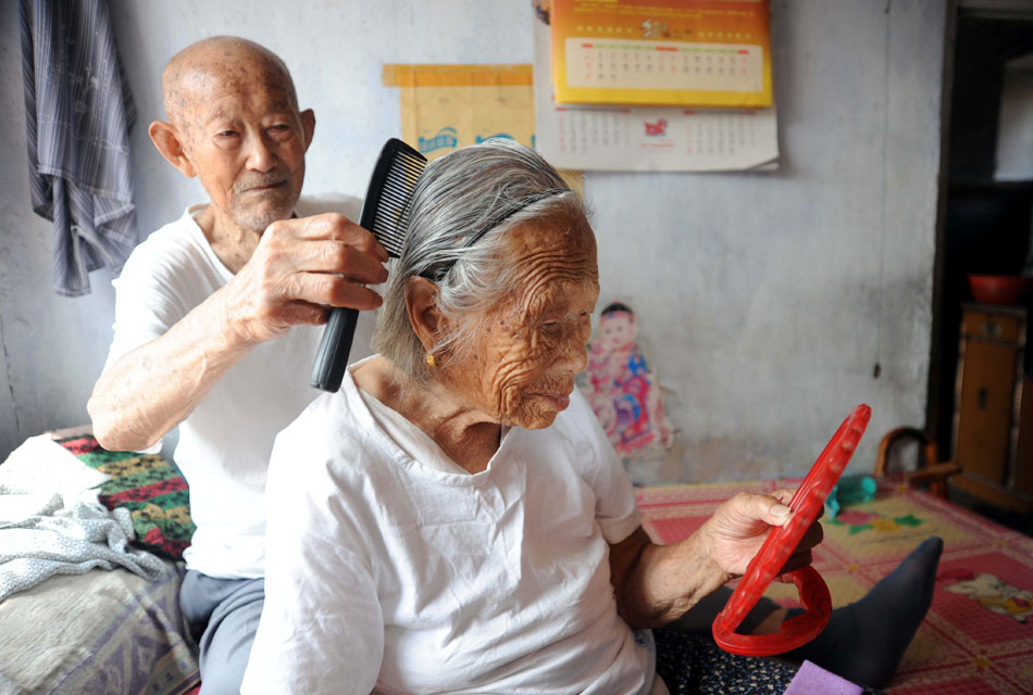 Aug. 21, 2012, two days ahead of Qixi Festival, or Chinese Valentine’s Day, was a day like any other day in the past 83 years for 99-year-old Gong Deyun and 102-year-old Sun Yucui (front). Gong combed wife’s hair and picked a flower for the upcoming Qixi Festival. (Xinhua/Liu Guoxian)