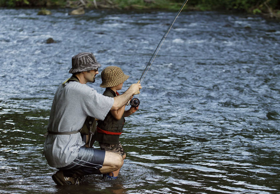 A father teaches his five-year-old son how to fish salmon in Spring Creek, Pennsylvania, the U.S., June 10, 2012.(Xinhua/Reuters)