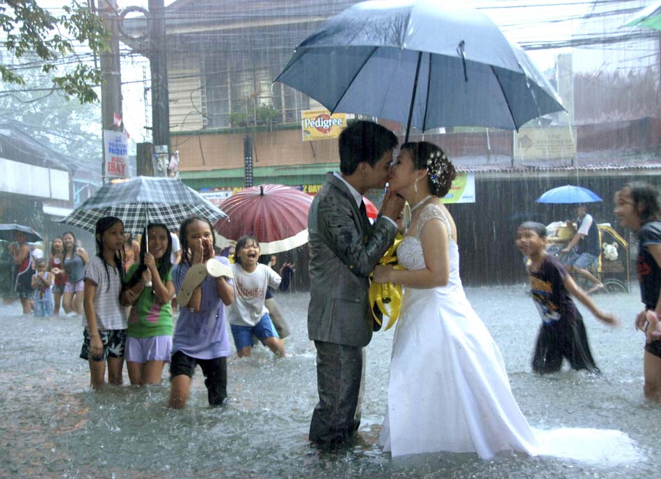 The newly married couple kiss each other on the street overflowed by the flood in Manila, the Philippines Dec. 8, 2012.(Xinhua/Reuters)