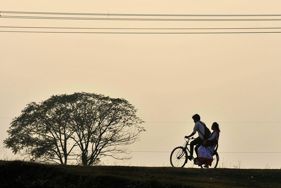 A man gives the girl a ride to home on his bike in the Darfur Barry village of Siliguri, India, Dec. 11, 2012.(Xinhua/AFP)