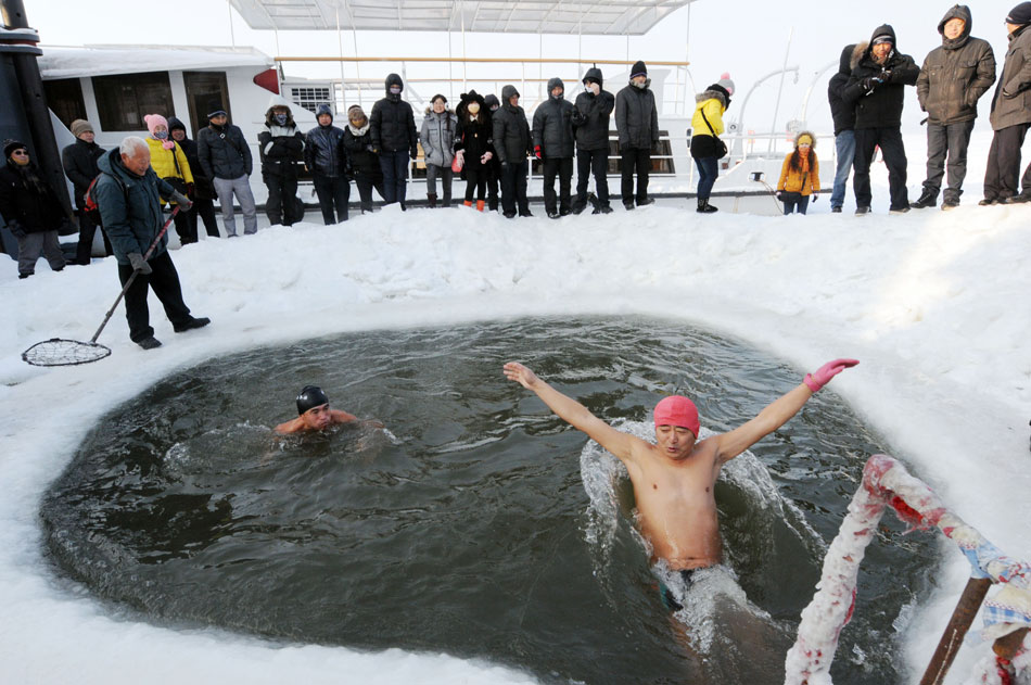 Tourists watch two men swimming in an icy pool in Harbin, capital city of northeast China’s Heilongjiang province, Dec. 17, 2012(Xinhua/Liu Yang)