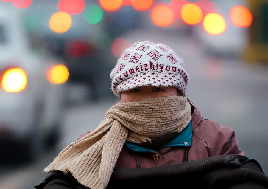 A women wrapped up in winter dresses travels on the road in Jinan, capital of east China's Shandong Province. The local meterological authority issued a blue warning against cold on Thursday. The lowest temperature will drop to -15 degrees centigrade starting Dec. 21. (Xinhua/Guo Xulei) 