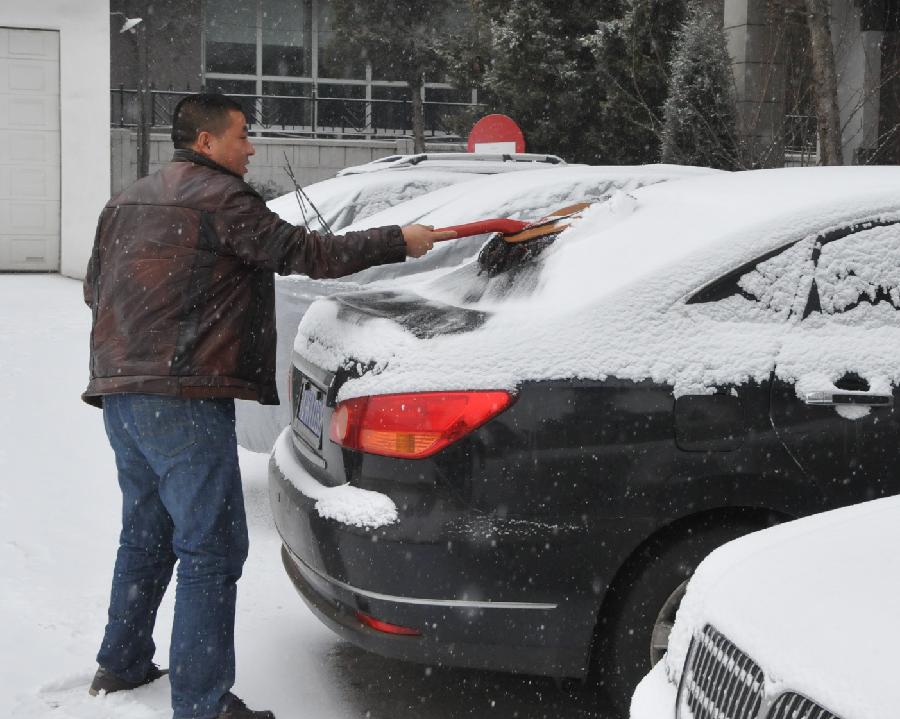 A citizen cleans the snow on his car at a street in Hohhot, capital of north China's Inner Mongolia Autonomous Region, Dec. 20, 2012. A heavy snow hit Inner Mongolia on Thursday, bringing a big temperature drop and winds to the region.(Xinhua/Liu Yide)