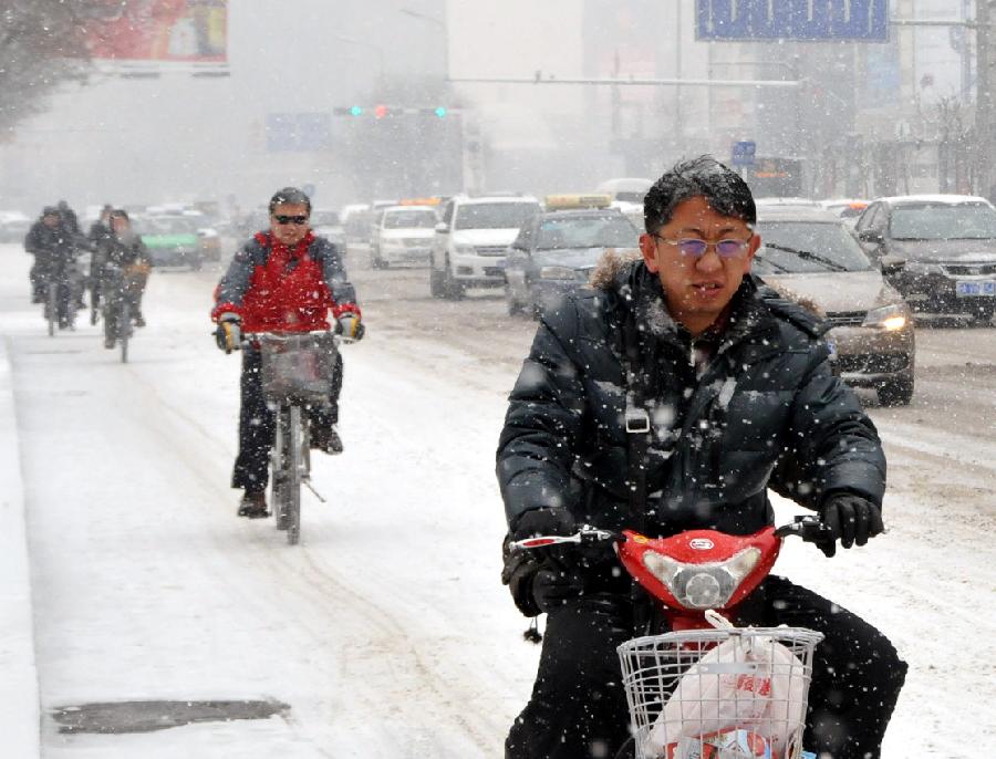 Citizens commute amid snow at a street in Hohhot, capital of north China's Inner Mongolia Autonomous Region, Dec. 20, 2012. A heavy snow hit Inner Mongolia on Thursday, bringing a big temperature drop and winds to the region.(Xinhua/Liu Yide) 