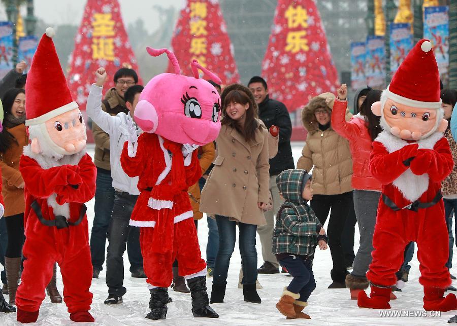 Tourists play with staff members who are dressed like Santa Claus in Happy Valley, an entertainment park, in east China's Shanghai, Dec. 21, 2012. A Christmas Carnival held by the entertainment park kicked off on Friday. (Xinhua/Pei Xin)  