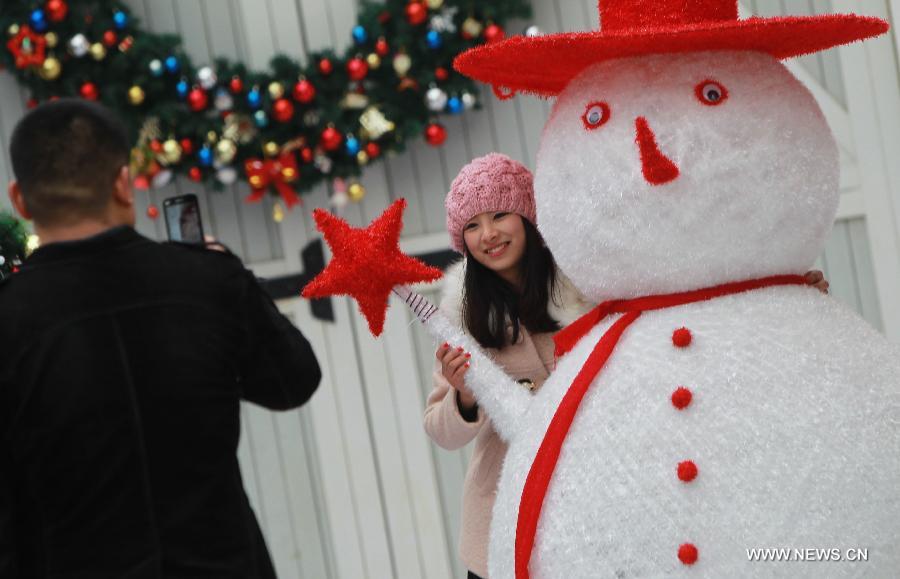 A woman poses for photo with a snowman in Happy Valley, an entertainment park, in east China's Shanghai, Dec. 21, 2012. A Christmas Carnival held by the entertainment park kicked off on Friday. (Xinhua/Pei Xin) 