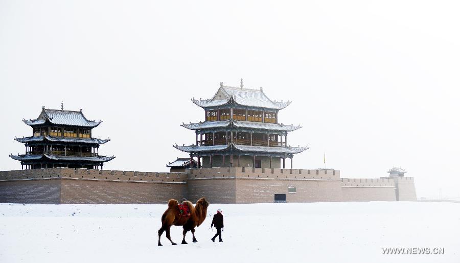 A woman walks with a camel beside the Jiayu Pass after snowfall in Jiayuguan City, northwest China's Gansu Province, Dec. 21, 2012. (Xinhua/Zhang Meng)