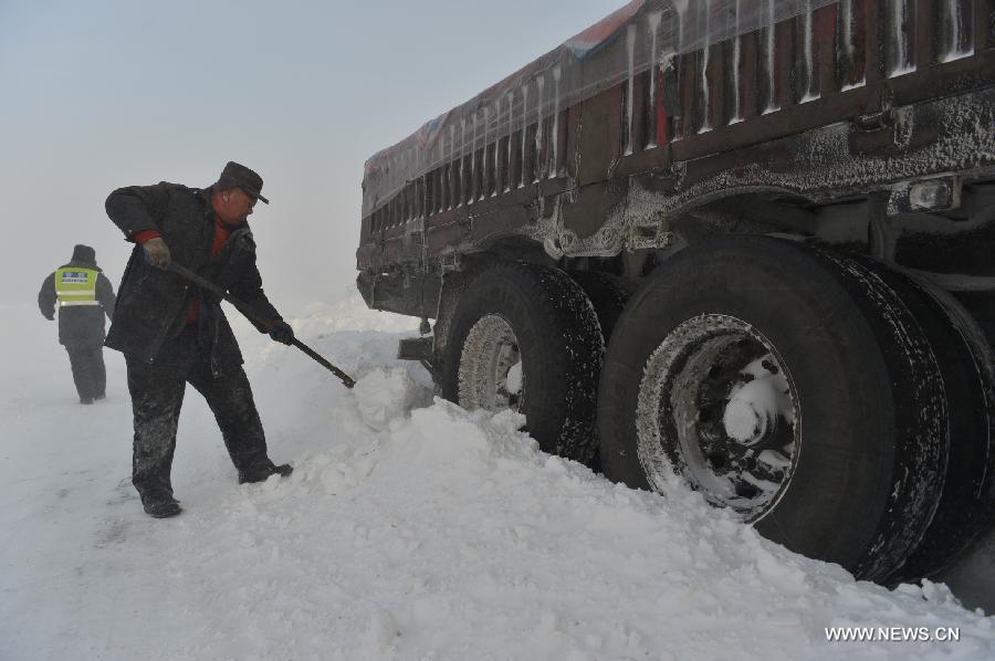 Traffic policeman and a passenger clear off snow on the blizzard-hit S303 road in Xialaoba Township of Kazak Autonomous County of Barkol in northwest China's Xinjiang Uygur Autonomous Region, Dec. 20, 2012. More than 800 vehicles and 1,000 people were trapped on roads amid a blizzard in the county and rescuers have transferred most vehicles and people to safe place. (Xinhua/Zhang Jiangang) 