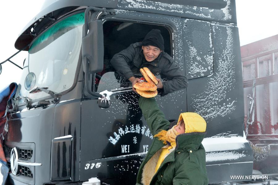 Rescuers send pancakes to trapped people on the blizzard-hit S303 road in Kazak Autonomous County of Barkol in northwest China's Xinjiang Uygur Autonomous Region, Dec. 20, 2012. More than 800 vehicles and 1,000 people were trapped on roads amid a blizzard in the county and rescuers have transferred most vehicles and people to safe place. (Xinhua/Zhang Jiangang)
