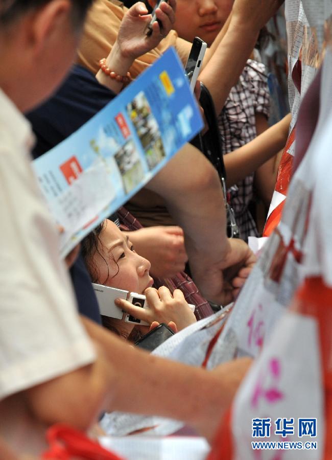 Parents look up whether their children are admitted by junior high school in anxiety in Nanjing on June 22, 2012. (Xinhua/Sun Can)