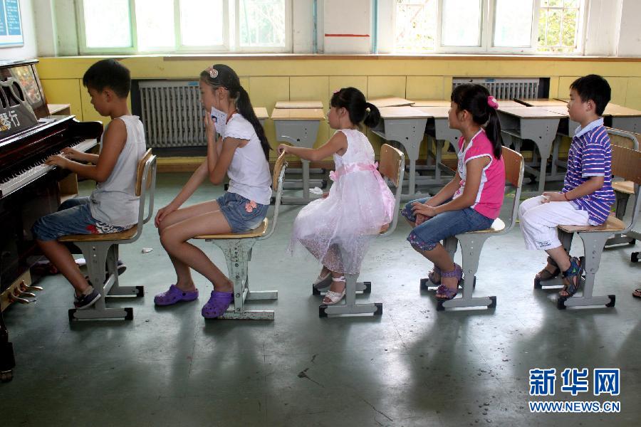 Several children wait in line to practice playing piano before the examination in Hefei, capital of east China’s Anhui Province, on Aug. 4, 2012. (Xinhua/Zhang Rui)