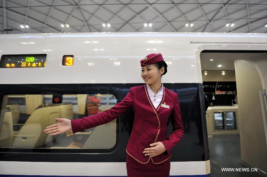 A stewardess waits for passengers by the G80 express train at Shijiazhuang Railway Station during a trip to Beijing, capital of China, Dec. 22, 2012.(Xinhua/Chen Yehua) 