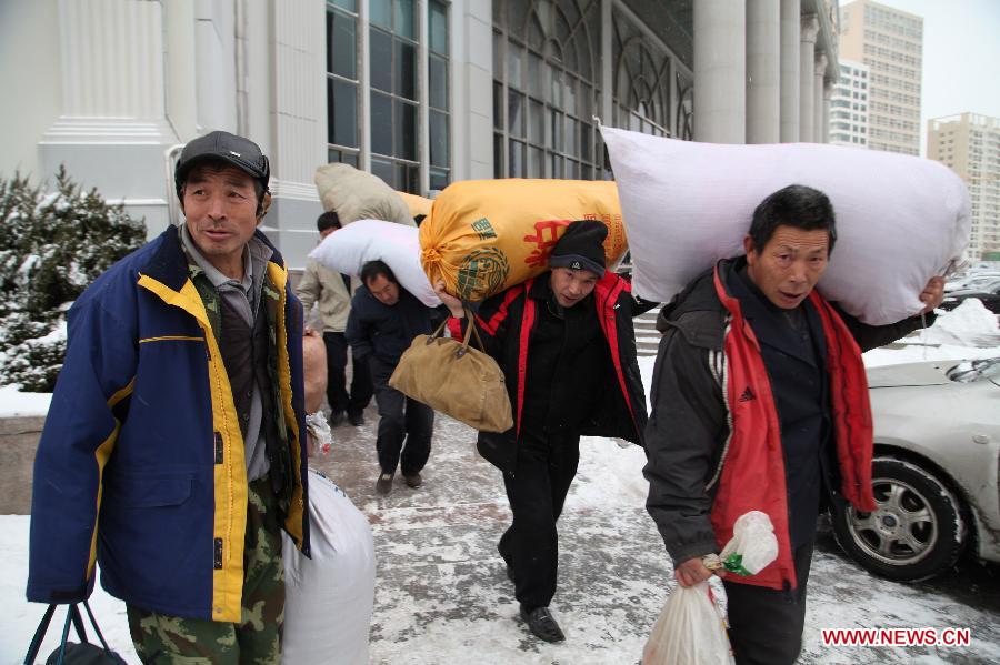 Workers walk out of a bus station with bags on back in Weihai, east China's Shandong Province, Dec. 23, 2012. A severe cold wave is sweeping most parts of China, with temperatures dropping by around 10 degrees Celsius in some areas. The local meteorological authority issued a blue alert for the cold wave. (Xinhua/Yu Qibo) 