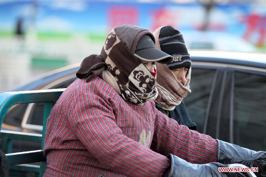 People travel on the road against the wind in Qinhuangdao, north China's Hebei Province, Dec. 23, 2012. A severe cold wave is sweeping most parts of China, with temperatures dropping by around 10 degrees Celsius in some areas. The local meteorological authority issued a blue alert for the cold wave on Sunday. (Xinhua/Wang Hanzhi) 