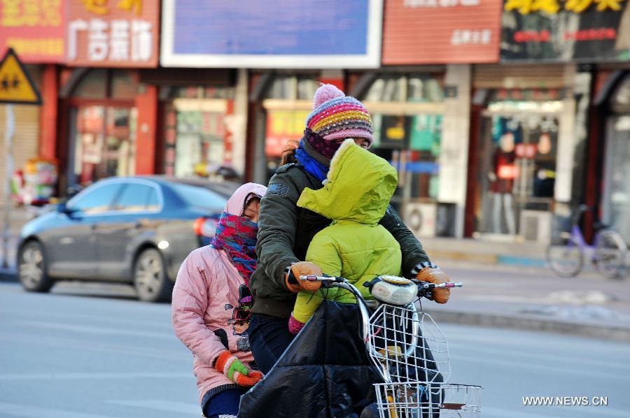 A local resident rides in chill wind in Baoding, north China's Hebei Province, Dec. 23, 2012. The provincial meteorological observatory issued a blue alert on cold wave on Saturday. Most parts of Hebei suffered from a sharp decline of temperatures and strong wind. (Xinhua/Zhu Xudong)