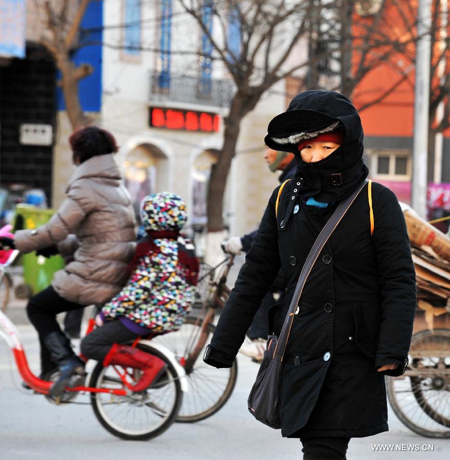 A local resident walks in chill wind in Baoding, north China's Hebei Province, Dec. 23, 2012. The provincial meteorological observatory issued a blue alert on cold wave on Saturday. Most parts of Hebei suffered from a sharp decline of temperatures and strong wind. (Xinhua/Zhu Xudong) 