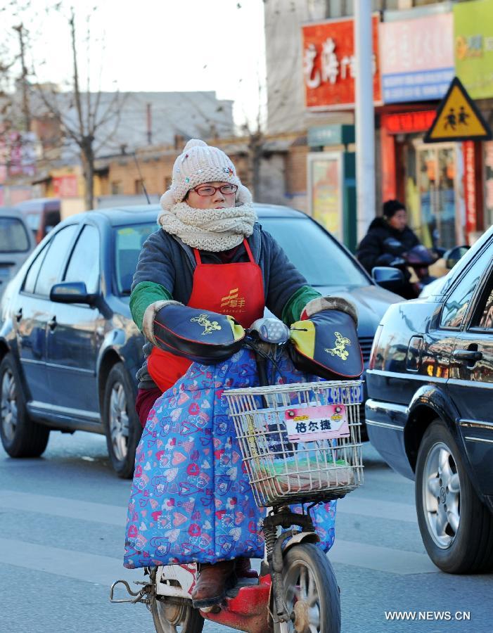 A local resident rides in chill wind in Baoding, north China's Hebei Province, Dec. 23, 2012. The provincial meteorological observatory issued a blue alert on cold wave on Saturday. Most parts of Hebei suffered from a sharp decline of temperatures and strong wind. (Xinhua/Zhu Xudong)