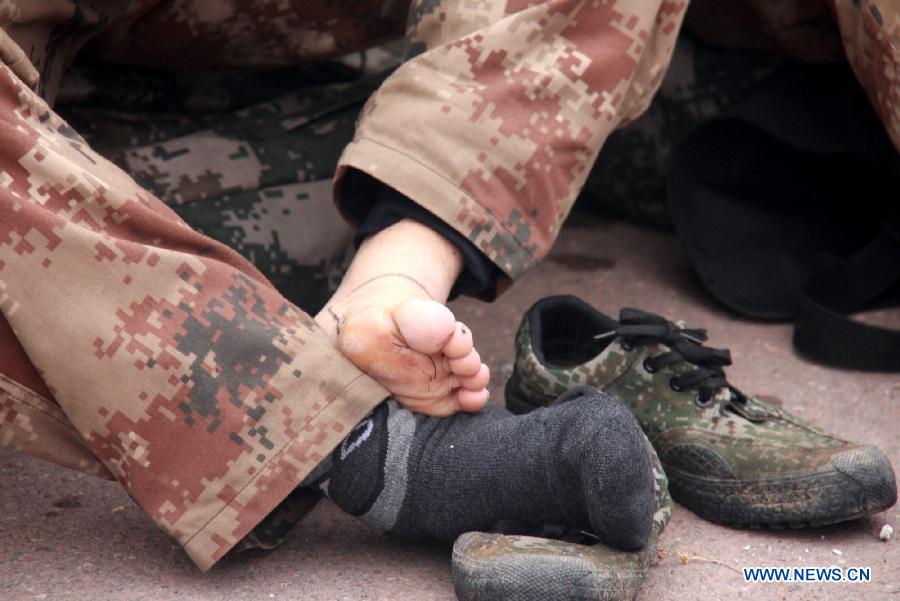 A soldier takes off his shoe to relieve blister ache on his foot during a military training in central China's Henan Province, Dec. 19, 2012. Thousands of soldiers went through harsh environment as they participated in the military training here. (Xinhua/Shen Dongdong)  