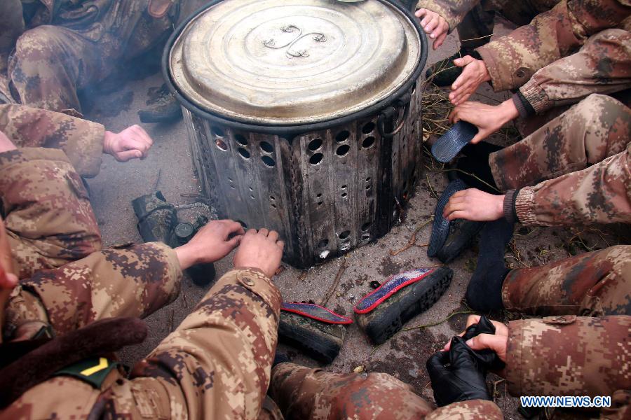 Soldiers gather to have their wet footwear dried up around an camp stove during a military training in central China's Henan Province, Dec. 19, 2012. Thousands of soldiers went through harsh environment as they participated in the military training here. (Xinhua/Shen Dongdong) 