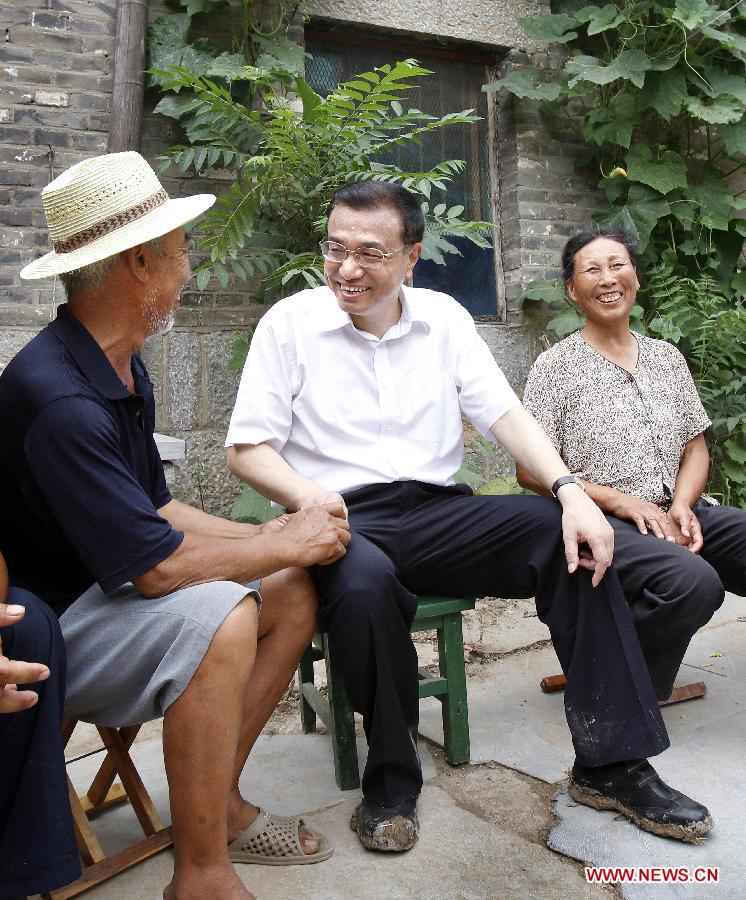 File photo taken on July 8, 2010 shows Li Keqiang (C) talks with family members of villager Su Shujie in Dasun Village of Jiaxiang County in Jining City, east China's Shandong Province. (Photo/Xinhua) 