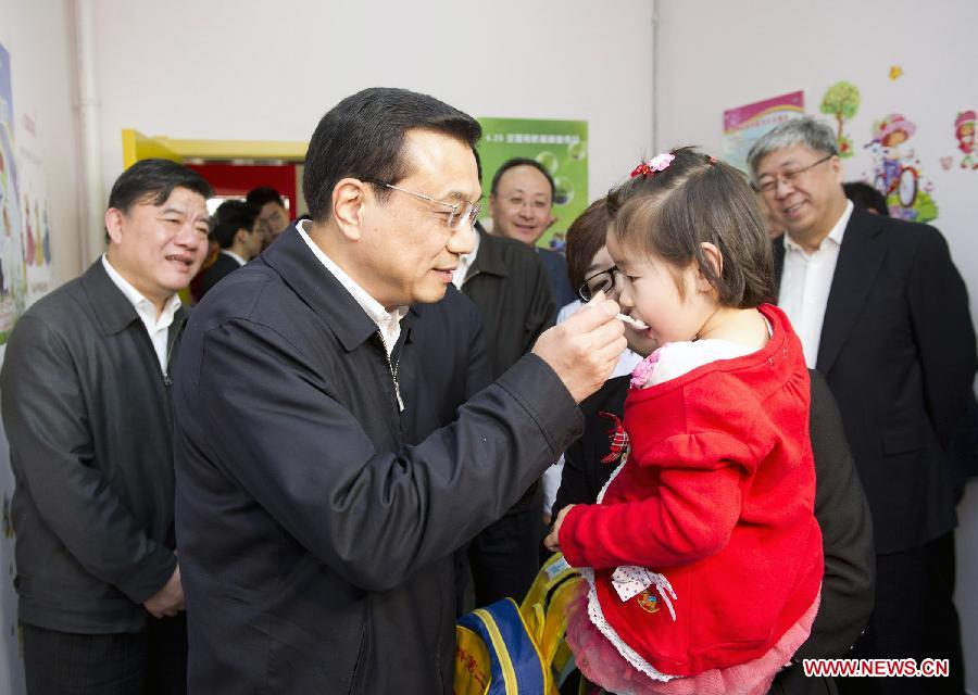 File photo taken on April 25, 2011 shows Li Keqiang (L, front) feeds a child with sugar-pill in a health service center in Fangzhuang community in Beijing, capital of China, as he attends activities celebrating the children's vaccination day and inspects the work of healthcare reform in Beijing. (Xinhua/Huang Jingwen) 