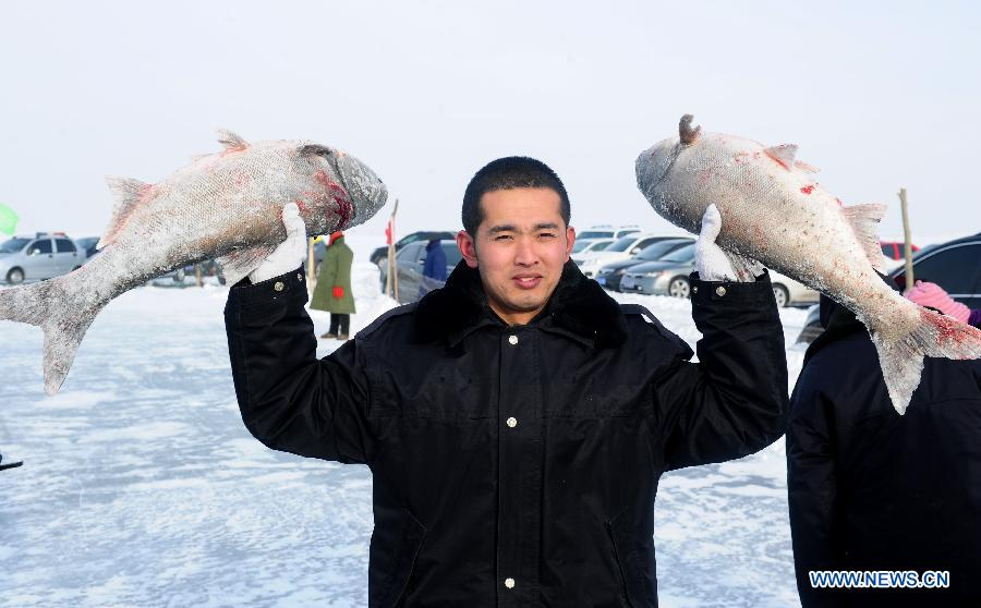 A man poses for a photo with fish during an ice fishing festival in Zhenlai County, northeast China's Jilin Province, Dec. 24, 2012. (Xinhua/Xu Chang) 