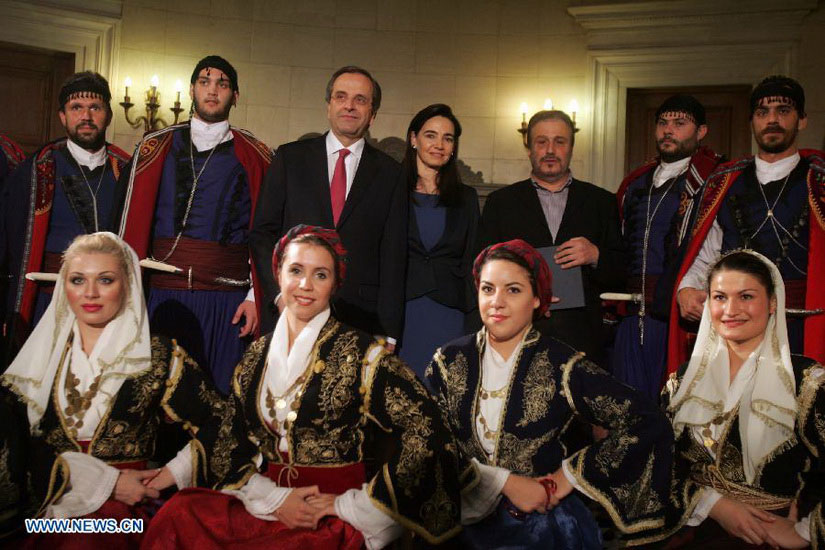 Greek Prime Minister Antonis Samaras (3rd L, rear) poses for photos with members of cultural clubs, dressed in traditional costumes, at Maximos Mansion, central Athens, Greece, Dec. 24, 2012. On Christmas Eve, traditional carols are sung throughout Greece, giving a tone of optimism in a country struck by the economic crisis. (Xinhua/Marios Lolos)