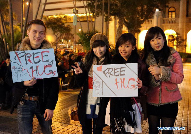 Citizens pose for photos with signs reading "free hug" at the Statue Square in Hong Kong, south China, on Dec. 24, 2012. (Xinhua/Li Peng) 