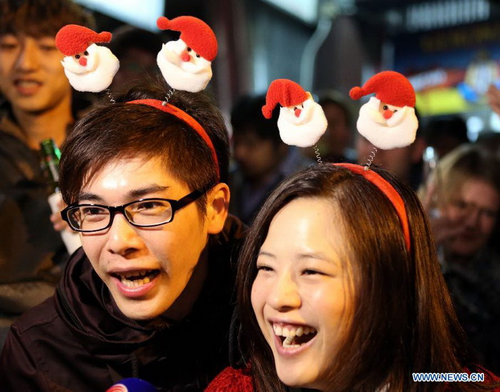 Two visitors with Christmas headwears are interviewed at Lan Kwai Fong, a commercial area in Hong Kong, south China, early Dec. 25, 2012. (Xinhua/Li Peng)