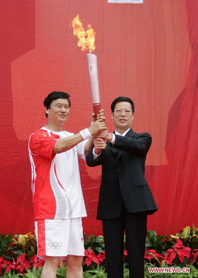 File photo taken on Aug. 1, 2008 shows Zhang Gaoli (R) hands the Olympic torch to Kong Xiangrui, who is a worker of Tianjin Port and a national model worker. (Xinhua/Song Ziming) 