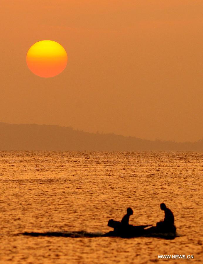 Tourists are silhouetted during the sunset along the Sanya Bay in Sanya, a famous tourism city in South China's Hainan Province, Dec. 25, 2012. (Xinhua/Hou Jiansen)