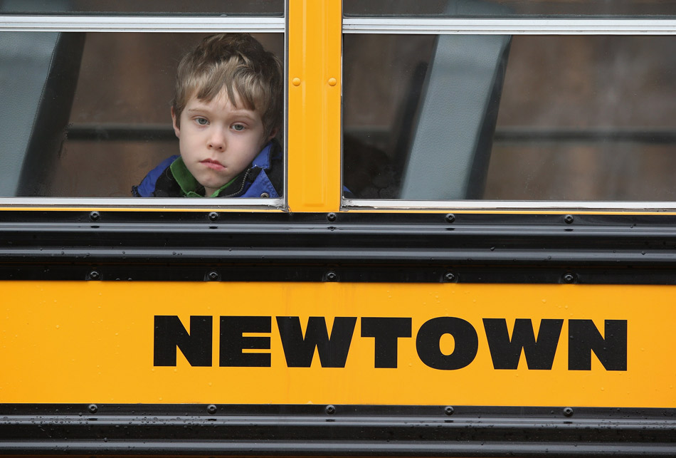 A boy sits in a school car, looking at the people attending the funerals of the victims in Sandy Hook Elementary School shooting incident, where a gunman opened fire on school children and staff in Newtown, Connecticut, Dec. 15, 2012. (Xinhua/AFP)