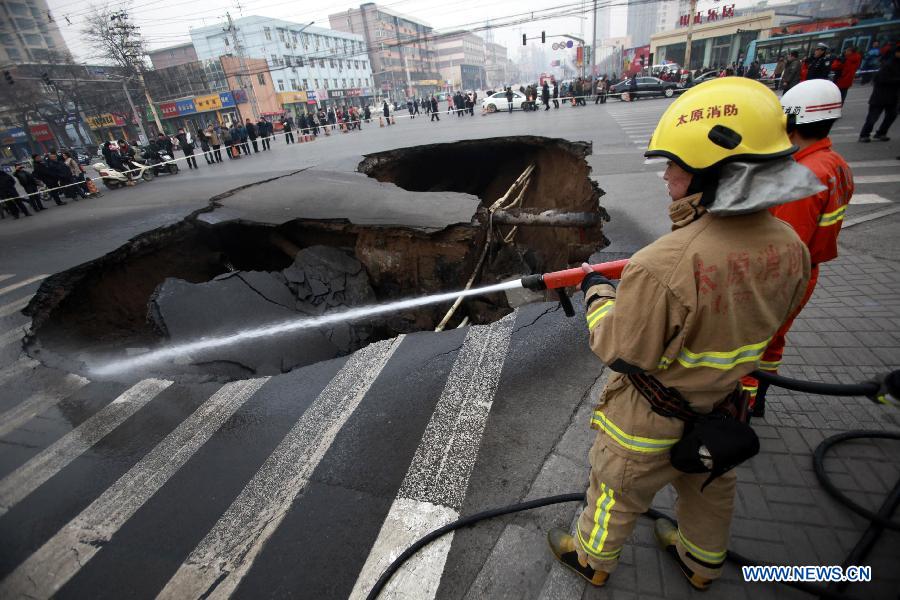 Firefighters work at the collapsed road intersection in Taiyuan, capital of north China' Shanxi Province, Dec. 26, 2012. A hole, measuring around 5 meters deep and 15 meters wide, appeared after the road section collapsed. No casualties were reported by far. (Xinhua/Shi Xiaobo)