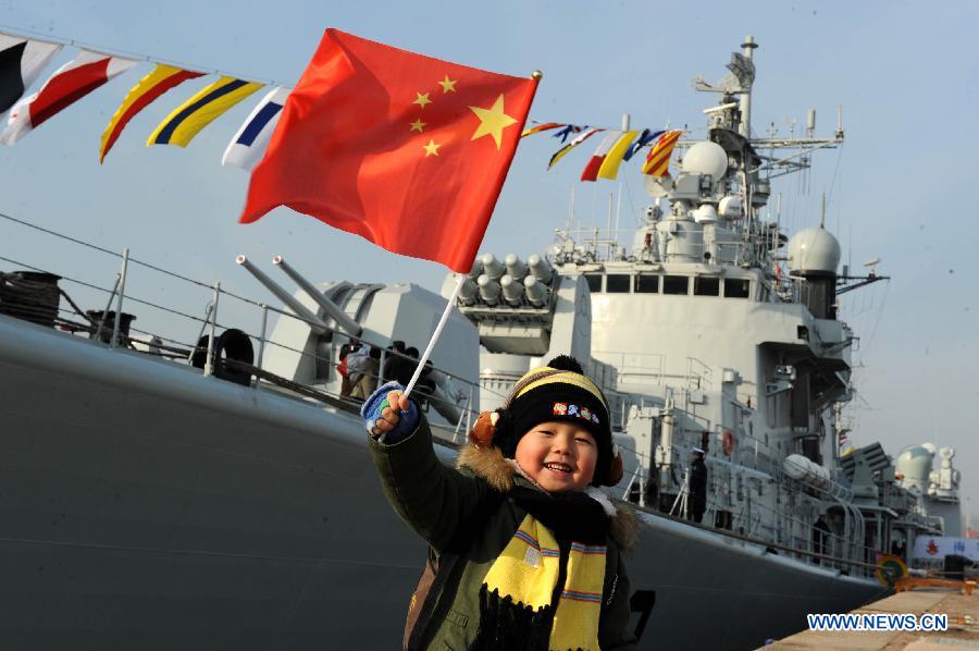 A boy waves the national flag in front of the missile destroyer "Qingdao" in Qingdao, east China's Shandong Province, Dec. 26, 2012. Four warships of the Chinese navy, including "Qingdao", "Zhoushan", "Guangzhou" and "Shenzhen", held an open day to public in their namesake cities on Wednesday. (Xinhua/Li Ziheng)