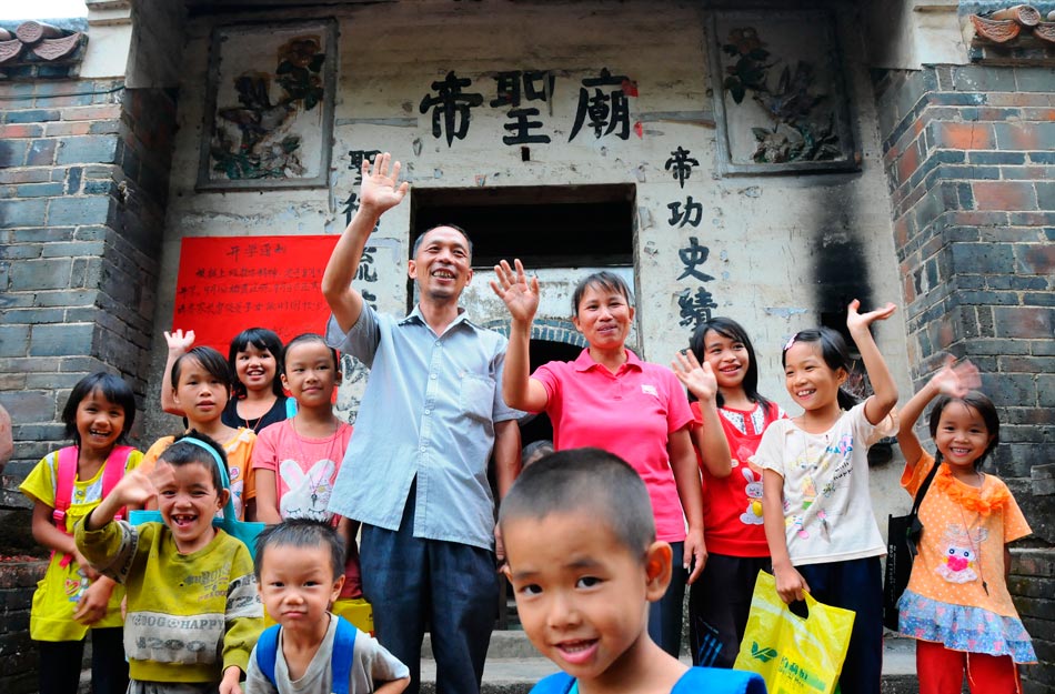 Liao Yahua and his wife Huang Duimei, who respectively serve as headmaster and teacher of a primary school, stand with their beloved students in front of the temporary classroom in Cenxi, Guangxi province, Sept. 10, 2012. (Xinhua/Zhang Zhoulai)