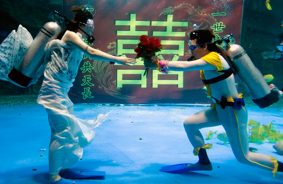 An underwater wedding ceremony is held in Jinan, capital of East China’s Shandong province,  May 19, 2012. Thousands of tourists and the fish shoal witnessed the special wedding. (Photo/Xinhua)