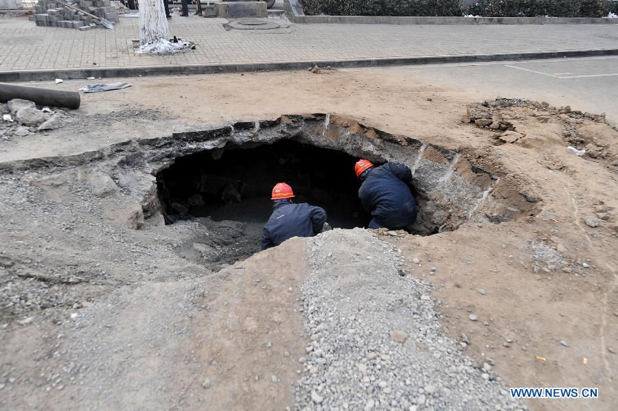 Workers check the collapsed section of the road intersection of Bingzhou North Road and Bingzhou East Street in Taiyuan, capital of north China's Shanxi Province, Dec. 27, 2012. 