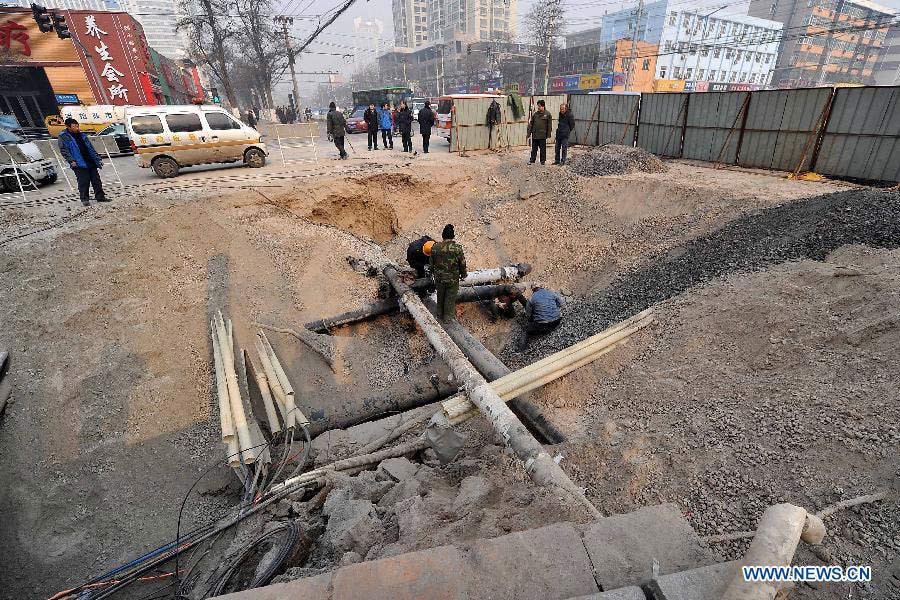 Workers repair the damaged pipelines at the collapsed section of the road intersection of Bingzhou North Road and Bingzhou East Street in Taiyuan, capital of north China's Shanxi Province, Dec. 27, 2012. 