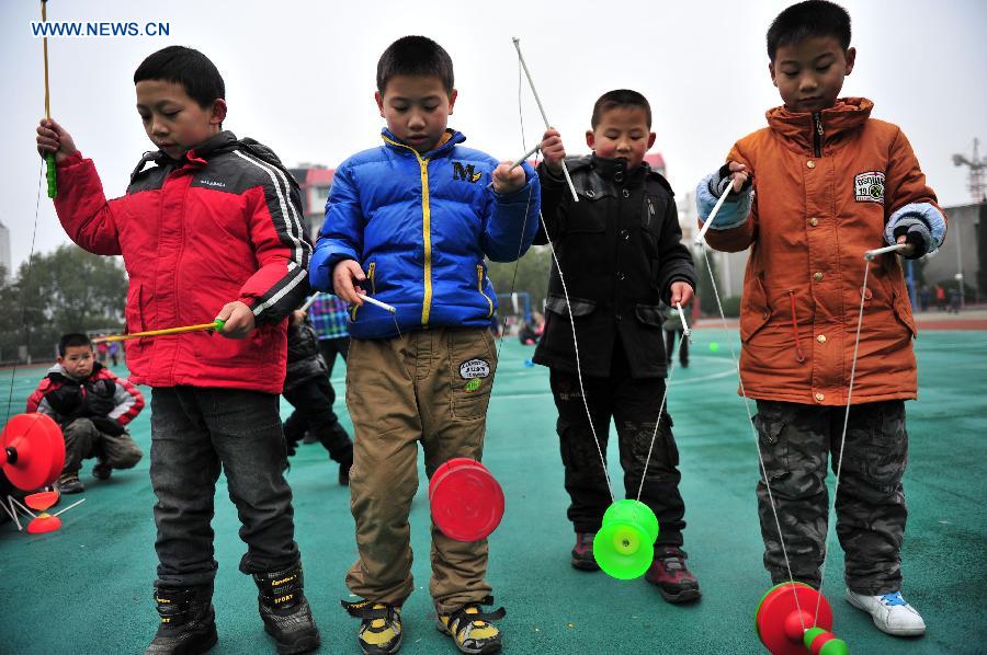 Pupils play traditional Kongzhu, also known as diabolo, at the playground of the Zigui experimental primary school in Zigui County, central China's Hubei Province, Dec. 27, 2012. Kongzhu literarily means empty bamboo, and is one of the major Chinese traditional toys along with shuttlecocks and kites. It is a popular activity among people of various ages. (Xinhua/Wang Huifu)