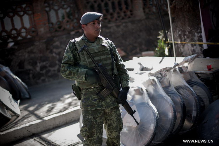 A Mexican Army soldier stands guard at a site where weapons are exchanged for groceries and cash by residents as part of "For your family, voluntary disarmament" program held at Iztapalapa Deputation, in Mexico City, capital of Mexico, on Dec. 27, 2012. (Xinhua/Pedro Mera)  