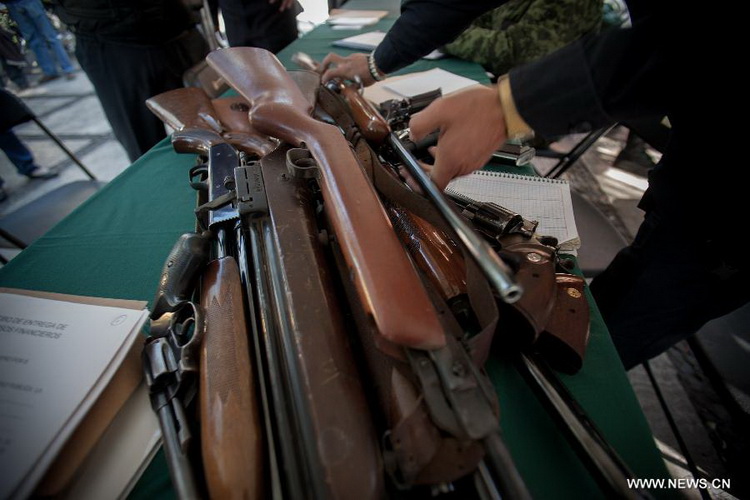 A Mexican Police officer inspects weapons which are exchanged for groceries and cash by residents as part of "For your family, voluntary disarmament" program held at Iztapalapa Deputation, in Mexico City, capital of Mexico, on Dec. 27, 2012. (Xinhua/Pedro Mera)