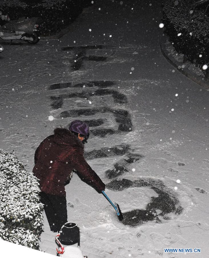 A local citizen practices calligraphy on a snow-covered road in Shijingshan community in Beijing, capital of China, Dec. 28, 2012. Beijing has witnessed the 7th snowfall in this winter on Friday. (Xinhua/He Junchang) 