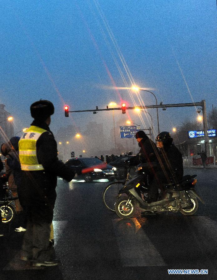 A traffic police directs the traffic at the Changchunjie crossing in snow in Beijing, capital of China, Dec. 28, 2012. Beijing has witnessed the 7th snowfall in this winter on Friday. (Xinhua/He Junchang)