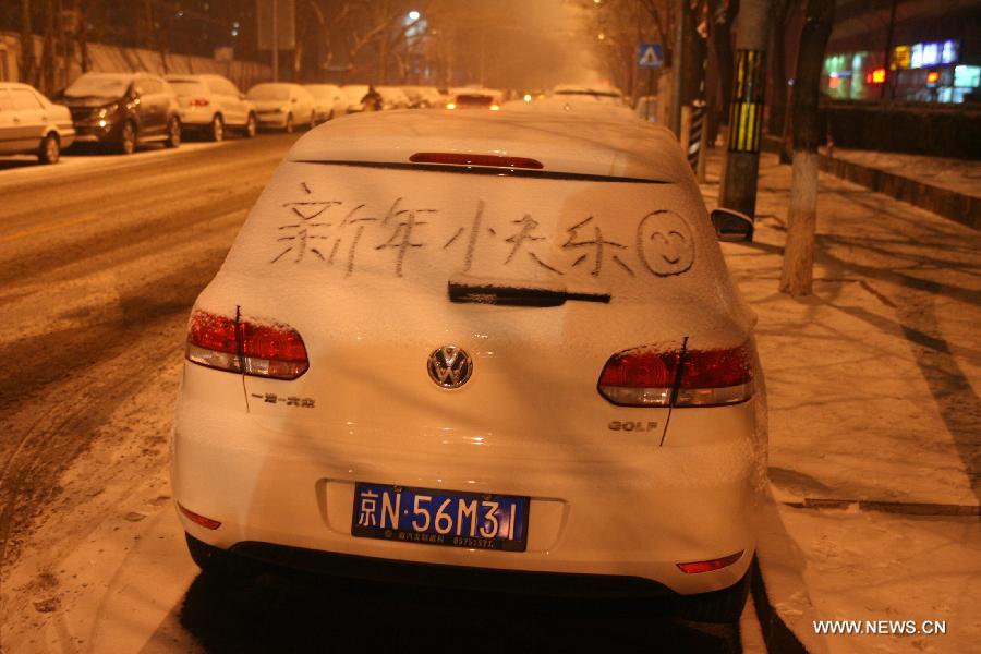 Photo taken on Dec. 28, 2012 shows "Happy New Year" written in Chinese on a car covered with snow in Beijing, capital of China. Beijing witnessed the 7th snowfall in this winter on Friday. (Xinhua/Yin Xubao)  