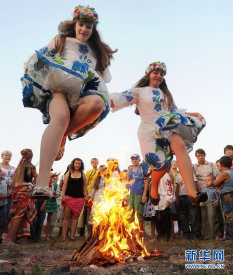 Girls wearing traditional costumes leap over the campfire in Ivan Kupala Festival in Minsk, Belarus on July 6, 2012. Bielorussians sing and dance around campfires at night in July to celebrate the coming of summer. (Xinhua/AFP Photo)
