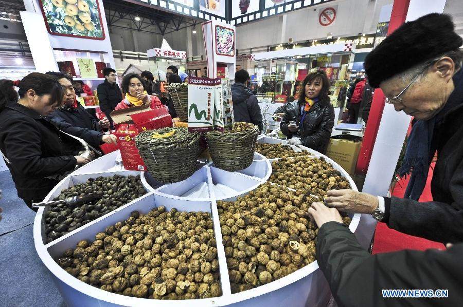 Consumers visit a nut dealer at the 2012 Beijing Tourism Product Expo in Beijing, capital of China, Dec. 28, 2012. The four-day expo was opened Friday at the China International Exhibition Center in Beijing. Tourism souvenirs, craftworks, business gifts, outdoor gears and cultural and creative products from about 1,000 exhibitors were demonstrated at the event. (Xinhua/Wang Jingsheng)