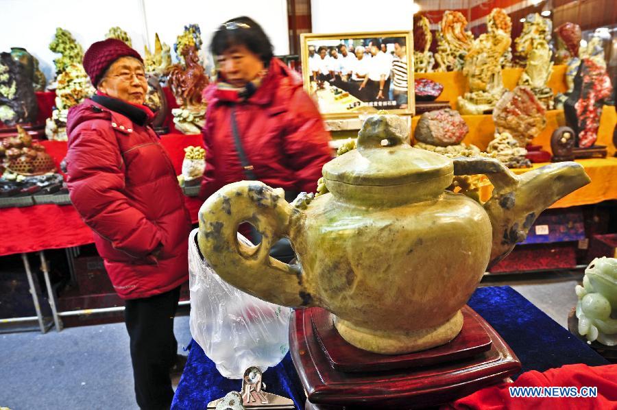 Two visitors look at a pyrophyllite teapot at the 2012 Beijing Tourism Product Expo in Beijing, capital of China, Dec. 28, 2012. The four-day expo was opened Friday at the China International Exhibition Center in Beijing. Tourism souvenirs, craftworks, business gifts, outdoor gears and cultural and creative products from about 1,000 exhibitors were demonstrated at the event. (Xinhua/Wang Jingsheng)